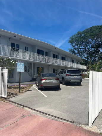 Two-story building with cars parked in front.