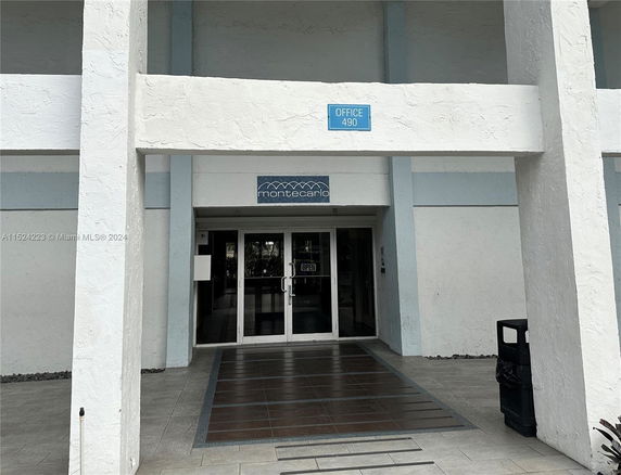Front view of a building entrance with glass doors and a sign above them.