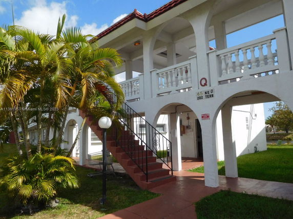 Front view of a two-story building with a red-tiled roof and arched entryways.