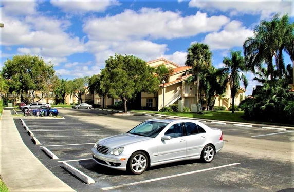Outdoor parking area with parked cars and trees nearby.