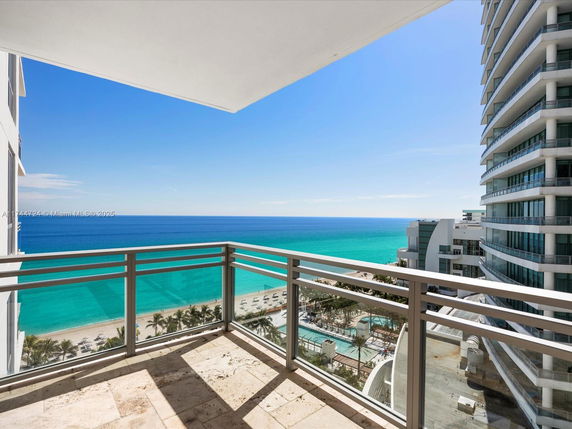 Balcony view of the ocean and neighboring buildings.