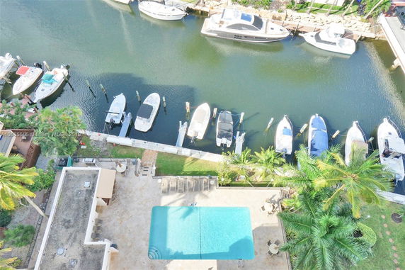 Aerial view of boats docked along a waterway, adjacent to a residential area with a pool.