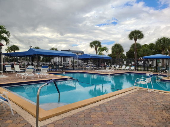 Outdoor swimming pool area with lounge chairs and blue canopies.
