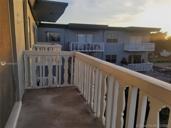 Balcony view overlooking an apartment building with white railings.