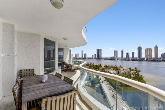 Balcony with outdoor furniture and a panoramic view of the city skyline and water.