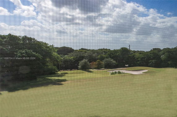 View of green landscape with trees and a sand pit.