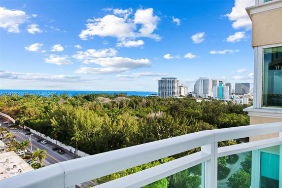 Panoramic view from a building showing surrounding greenery, distant ocean, and urban skyline.