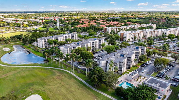 Aerial view of multiple residential buildings with surrounding greenery and parking areas.