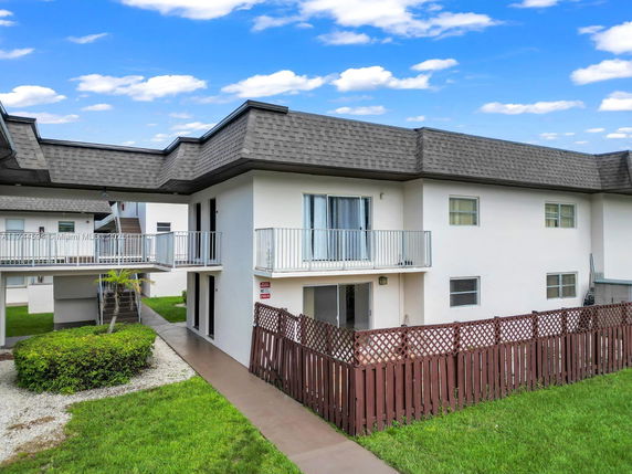 Front view of a two-story building with balconies and a wooden fence.