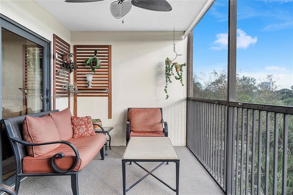 Outdoor balcony area with seating and plants, overlooking greenery.