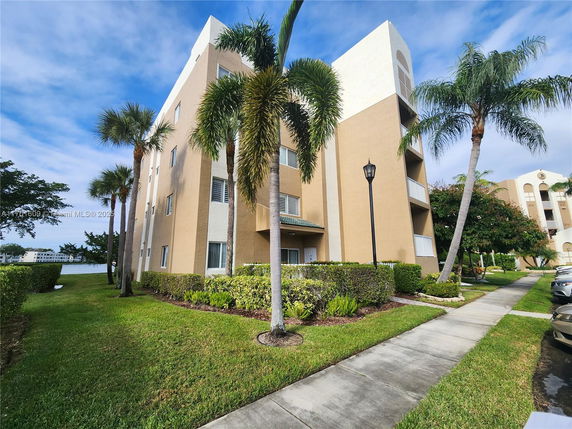 Front view of a multi-story residential building with palm trees.