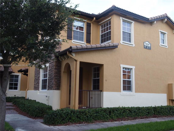 Front view of a two-story house with tan exterior and tile roof.