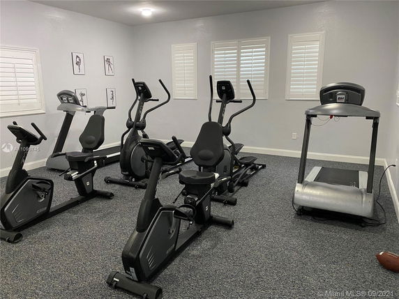 Room with exercise equipment including treadmills and stationary bikes.