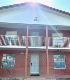 Front view of a two-story brick house with a balcony.