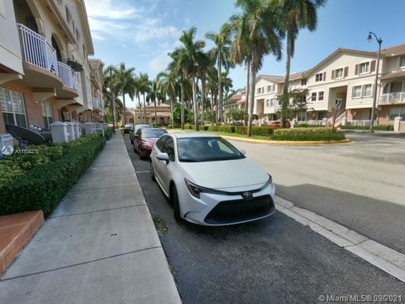 Outdoor parking area with cars parked along a residential street.