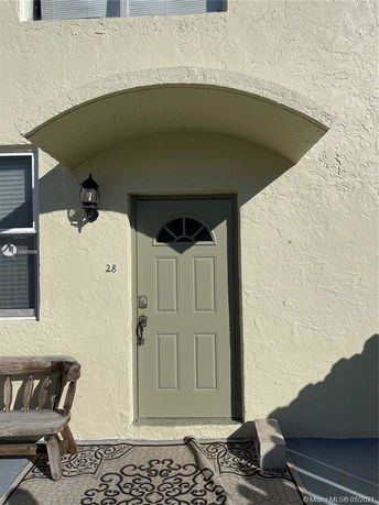 Front view of an entrance to a house with a green door and arched canopy.