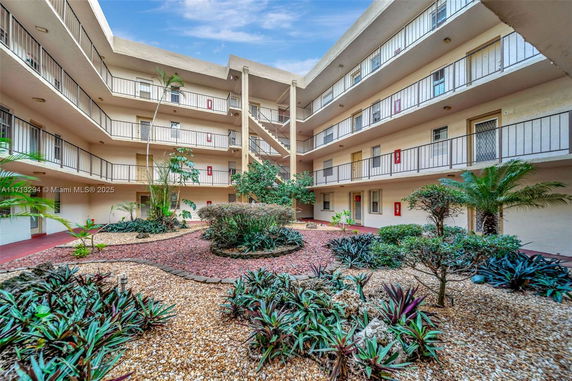 View of a multi-story building with open corridors surrounding a central courtyard with plants.