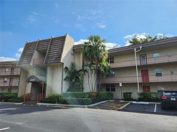 Front view of a multi-story apartment building with balconies and an entrance canopy.