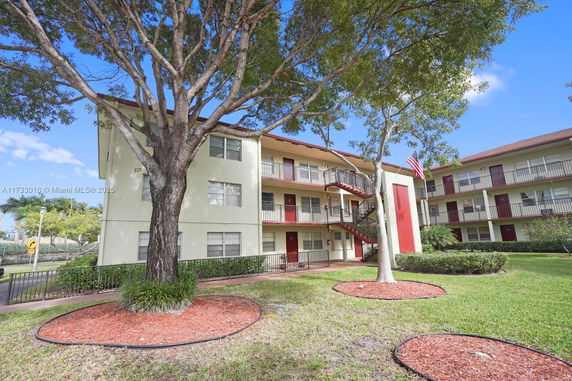 Front view of a three-story apartment building with external staircases and red doors.