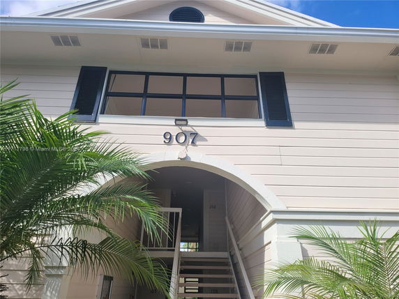Front view of a two-story building with arched entrance and black shutters.
