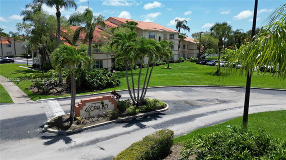 Front view of a multi-story condominium building with reddish-brown roofs and light-colored walls.