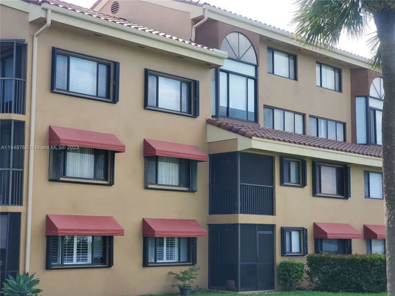 Front view of a multi-story building with awning windows and a tiled roof.