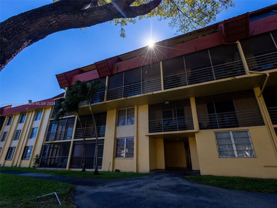 Front view of a multi-story residential building with balconies and a red roof.