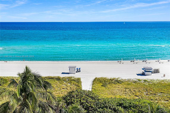 Panoramic view of a beach and ocean with clear blue water and sandy shore.
