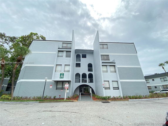 Front view of a multi-story building with a central arch and geometric design elements.