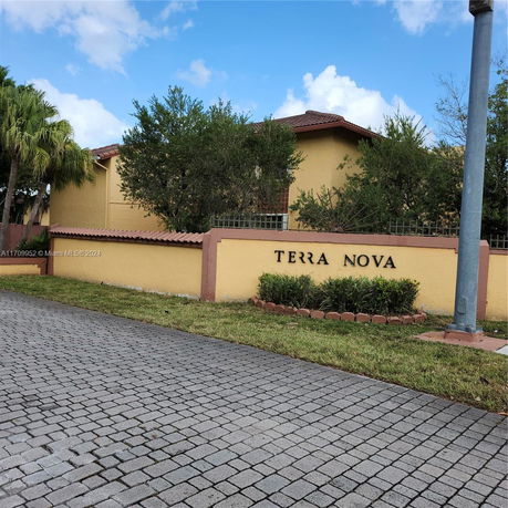 Front view of a building with a yellow exterior and a tiled roof, featuring a sign that reads 'TERRA NOVA'.