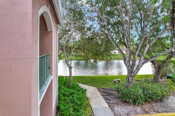 Oblique view of a building corner near a tranquil water body with surrounding trees.