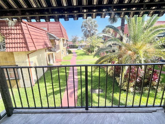 View from a balcony showing a courtyard with pathways and greenery, surrounded by buildings with red-tiled roofs.