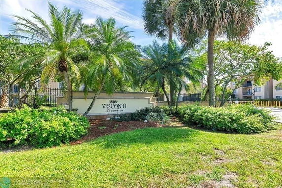 Entrance sign of Visconti Condominium surrounded by palm trees and greenery.