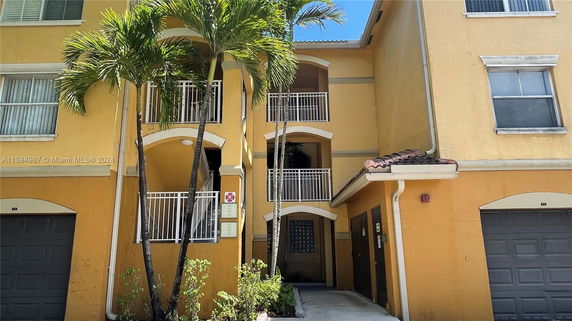 Front view of a multi-story building with yellow exterior and balconies.