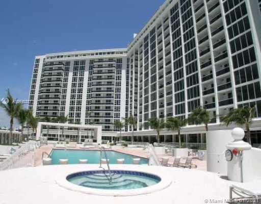 View of a large residential building with a swimming pool and a hot tub in the foreground.