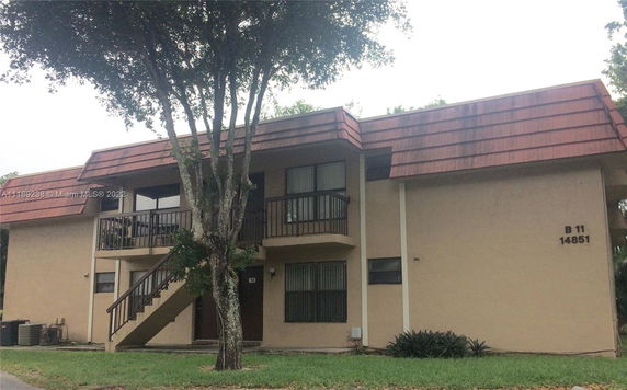Front view of a two-story apartment building with exterior stairs and a reddish-brown roof.