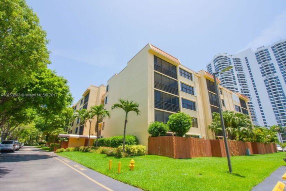 Front view of a multi-story apartment building with a landscaped lawn.