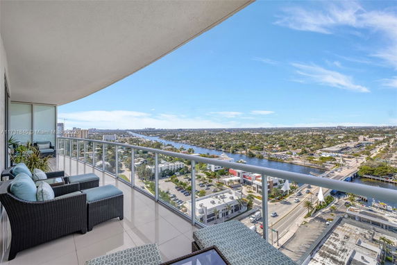 Panoramic view from a high-rise balcony overlooking a cityscape and waterway.