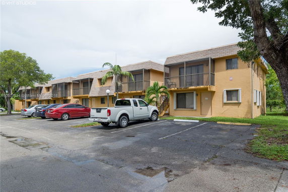 Front view of a two-story building with a parking area in front.