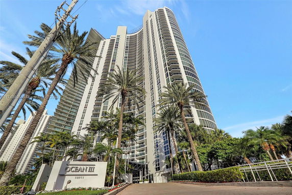 Front view of a tall residential building with multiple balconies.