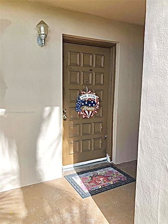 Front view of a house entrance with a decorated door and a doormat.