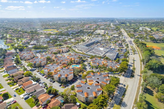 Aerial view of a residential and commercial area with buildings, roads, and surrounding landscape.