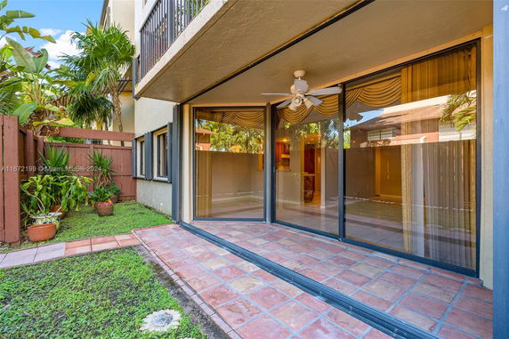 Front view of a building showing a patio area with sliding glass doors and balcony above.