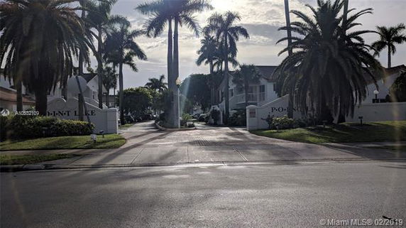 Front view of a residential complex with palm trees and entrance gate.