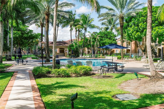 Outdoor swimming pool area with palm trees and lounge chairs.