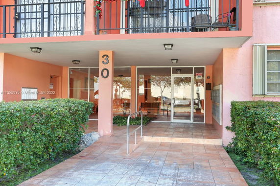 Front view of a building entrance with a glass door and balcony above.