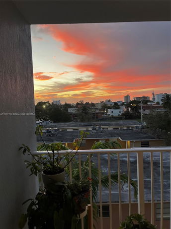 View from a balcony overlooking buildings under a colorful sunset sky.