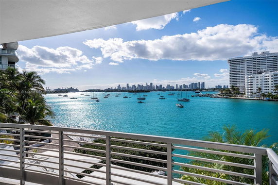 View from a balcony overlooking a body of water with boats and a city skyline in the distance.