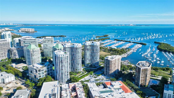 Aerial view of modern high-rise buildings next to a waterfront with numerous boats and yachts.