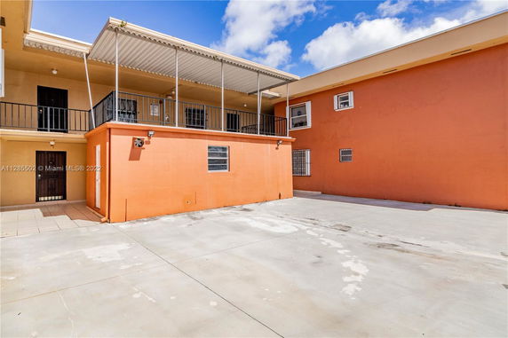 Front view of a two-story building with a covered balcony and orange facade.